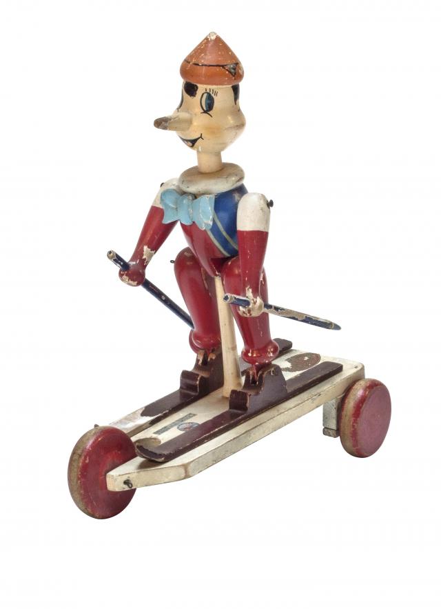Pinocchio sciatore. Trainato Pinocchio muove piedi e mani mentre scia; è presente anche il marchio del rivenditore, giocattoli sport carrozzelle F. GUERM Alessandria.