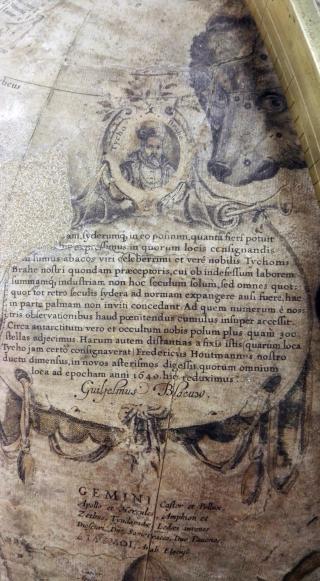 L’immagine mostra un cartiglio sormontato dal ritratto di Thyco Brahe. L'iscrizione in latino è un tributo alle osservazioni astronomiche di Brahe e di Frederick de Houtman, da cui attinge Blaeu per la realizzazione del globo celeste.