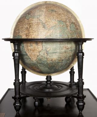 L’immagine raffigura un globo terracqueo su base lignea a crociera in stile olandese. Rappresentati continenti, paesi e città, oceani e mari. Dediche, vignette e disegni completano la superficie del globo.