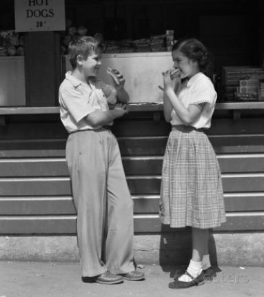 Boy And Girl Eating Hot Dogs at take out stand