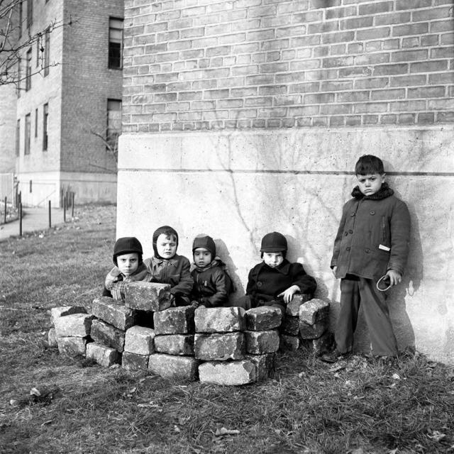 Children hiding behind the stone wall