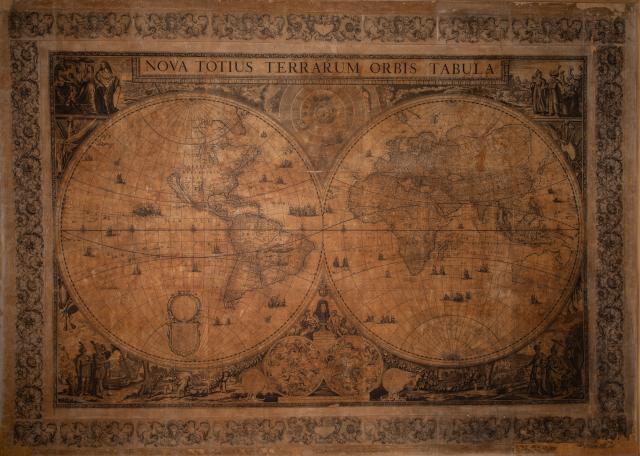 L’immagine rappresenta il mappamondo di De Wit, che raffigura i continenti allora conosciuti, il sistema copernicano, la mappa celeste delle costellazioni e allegorie dei continenti